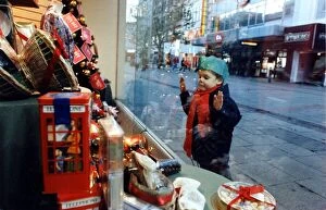 Images Dated 17th December 1991: Christmas - A young child peers at the Christmas decorations