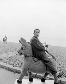 00140 Gallery: Comedian and actor Norman Wisdom photographed on Brighton Beach on a stuffed donkey