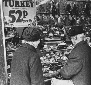 Couple looking at meat products on display in butchers shop, Cardiff, Wales Couple looking at meat products on display in butchers shop, Cardiff, Wales