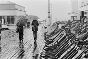 A couple walk along the deserted pier in Blackpool as the rain arrives to interrupt a
