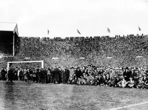 Crowds sit in the goalmouth after they came on to the pitch before the start of the game Crowds sit in the goalmouth after they came on to the pitch before the start of the game