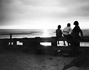 Darkness falls around three children as they watch the sunset at Rye Bay, Sussex Darkness falls around three children as they watch the sunset at Rye Bay, Sussex