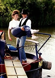 David Essex singer and actor on a barge boat carring a woman in a scene from his TV