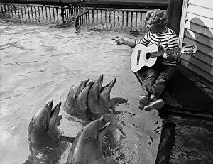 The Dolphins gather round to listen to Kay Smart singing, with guitar accompaniment