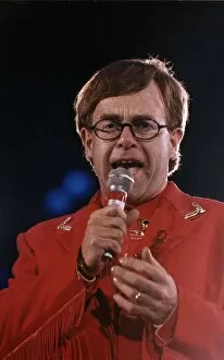 Images Dated 20th April 1992: Elton John circa 1992 Wearing Red Suit as he holds microphone during a Freddie