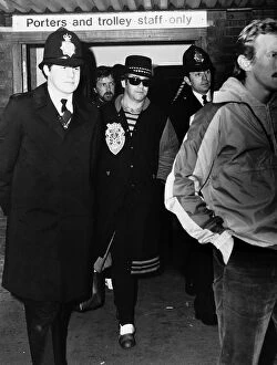 Images Dated 23rd December 1980: Elton John, pictured at Heathrow Airport, surrounded by police after getting off