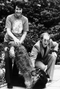 Elton john the singer with woman and two dogs on patio Elton john the singer with woman and two dogs on patio