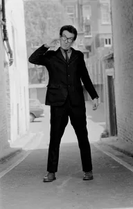 Elvis Costello, the newest sensation on the music scene, standing in small street Elvis Costello, the newest sensation on the music scene, standing in small street