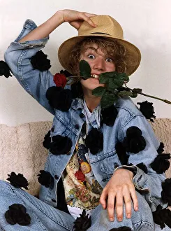 Emily Lloyd Actress sitting with hand on top of hat and with red rose in teeth Emily Lloyd Actress sitting with hand on top of hat and with red rose in teeth