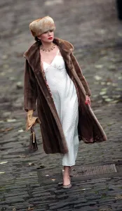 Evita Fashion Model wearing brown fur coat and hat white slip dress handbag gold Evita Fashion Model wearing brown fur coat and hat white slip dress handbag gold