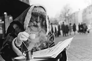 Father Christmas sitting outside a cafe in Paris, reading the newspaper Father Christmas sitting outside a cafe in Paris, reading the newspaper