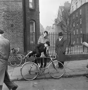 Father watches his son trying out cycles for sale at the flea market in Club Row Father watches his son trying out cycles for sale at the flea market in Club Row
