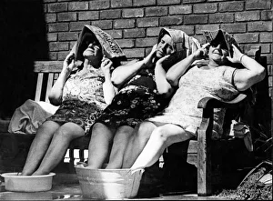 Three female old age pensioners sit out in the sun, cooling their feet in buckets of Three female old age pensioners sit out in the sun, cooling their feet in buckets of
