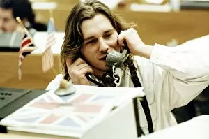 Finance Stock Exchange dealer sitting at desk Holding two telephones to each ear