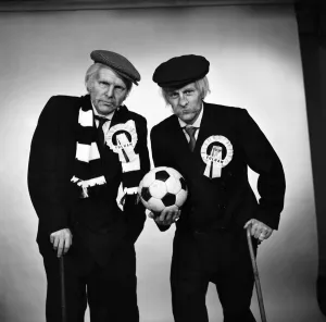 Images Dated 15th April 1975: Fulham footballers Bobby Moore (left) and Alan Mullery dressed in suits and make-up