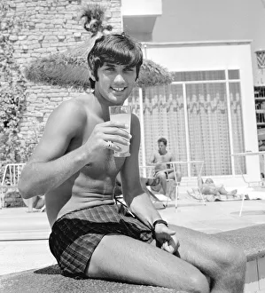 George Best relaxing on holiday with a drink and sitting on the edge of a swimming pool George Best relaxing on holiday with a drink and sitting on the edge of a swimming pool