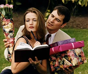 Girl writing in her diary while boyfriend tries to give her presents chocolates Girl writing in her diary while boyfriend tries to give her presents chocolates