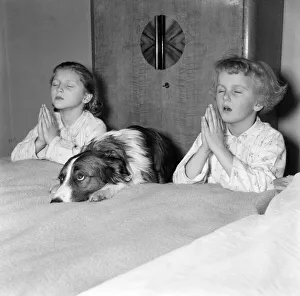 Two girls and dog praying. 21st December 1954 Two girls and dog praying. 21st December 1954