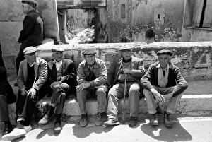 A group of pensioners sitting down against a wall on a street in a French village A group of pensioners sitting down against a wall on a street in a French village
