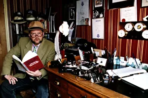 James Whale TV and Radio Presenter Sitting at desk holding book James Whale TV and Radio Presenter Sitting at desk holding book