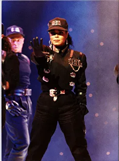Janet Jackson on stage right arm outstretched wearing baseball cap performing Janet Jackson on stage right arm outstretched wearing baseball cap performing