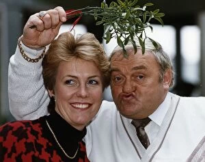 Jill Dando TV Presenter with Les Dawson who is holding mistletoe over their heads
