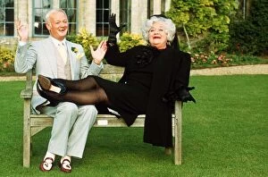Core204 Gallery: John Inman Comedy Actor and Mollie Sugden Comedy Actress sitting on wooden bench seat in