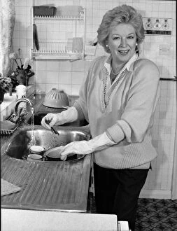 June Whitfield, TV actress, at her home in Wimbledon doing the washing up in her
