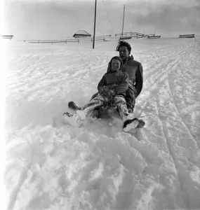 Man and girl on a wooden sledge in the snow at a resort in Switzerland Man and girl on a wooden sledge in the snow at a resort in Switzerland