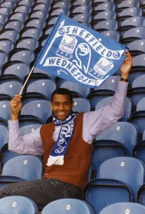 Images Dated 1st April 1993: Mark Bright footballer for Sheffield Wednesday sits in seats and waves a flag