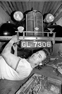 Mechanic underneath a car, making repairs April 1975 75-02158-010