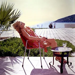 Melanie lost in her thoughts relaxes by the sea with a glass of red wine. Circa 1965 Melanie lost in her thoughts relaxes by the sea with a glass of red wine. Circa 1965