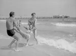 Two men throwing a young woman into the sea on Bournemouth beach. 10th Aust 1952 Two men throwing a young woman into the sea on Bournemouth beach. 10th Aust 1952