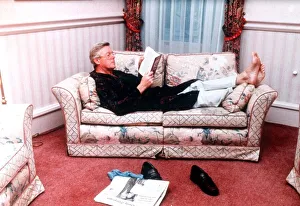 Michael Aspel TV Presenter of This is your Life lying on sofa reading book Michael Aspel TV Presenter of This is your Life lying on sofa reading book