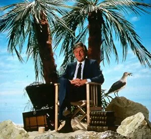 Michael Parkinson TV chat show presenter April 1986 sitting on a chair desert island palm