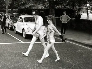 00007 Prints: Print of Bill Bailey and Marie Adams crossing Bayswater Road naked