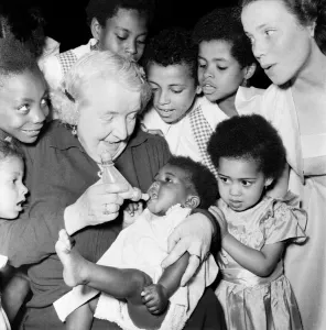 00021 Prints: Print of Mrs. Ada Wheeler bottle feeding a foster child, July 1953