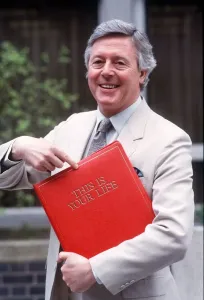 Michael Aspel holding red book Print