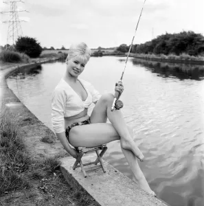Beachwear Model Prints: Clothing: Fashion: Beachwear: Model by the river bank fishing. August 1963 E490-005