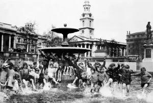 Prints of A crowd of children cool off in one of the fountains in Trafalgar Square during the Whitsun holiday St Martins in the Field Childhood Sitting on fountain Trousers rolled up Summer Cooling Off Weather Prints: Trafalgar Square Children Cooling Off Print May 1926