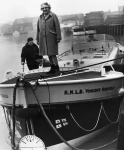 RNLI Prints: Print of an elderly woman standing next to a lifeboat