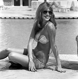 Images Dated 7th April 1975: Model wearing a bikini and sunglasses as she sits by the side of a swimming pool in