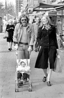 Mother and father pushing their little daughter along in a bugg on the streets of Mother and father pushing their little daughter along in a bugg on the streets of