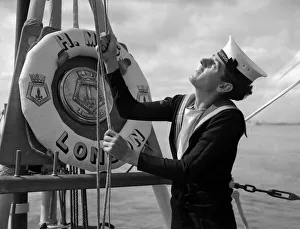 A naval rating raising the white ensign aboard the County Class cruiser HMS London which A naval rating raising the white ensign aboard the County Class cruiser HMS London which