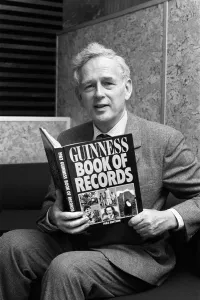 Norris McWhirter holding a copy of the Guinness Book of records Norris McWhirter holding a copy of the Guinness Book of records