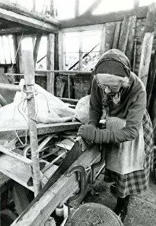Old lady sawing wood. Miss May Savidge had her 500 year old house dismantled