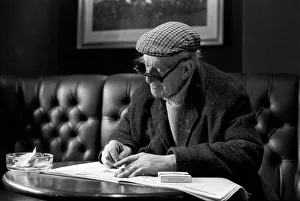 Pensioner: Elderly man filling his pools coupon whilst enjoying a cigarette Pensioner: Elderly man filling his pools coupon whilst enjoying a cigarette