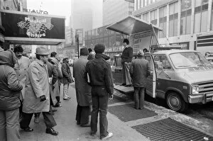 People listening to a man speaking from a platform on his van
