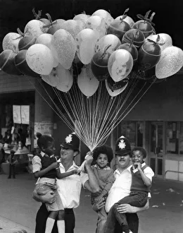 Two policemen holding three young boys in their arms with lots of toy Balloons Two policemen holding three young boys in their arms with lots of toy Balloons