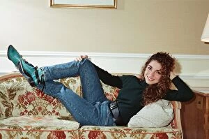 Images Dated 31st October 1988: Pop singer Gloria Estefan poses lying down on a sofa in her hotel room on a visit to